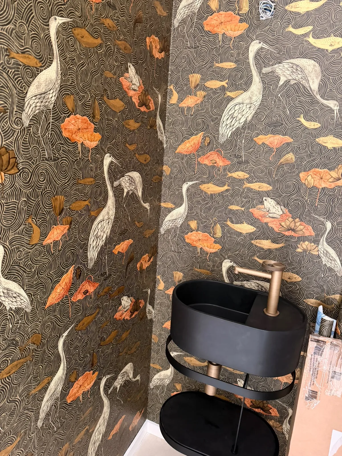 Papier peint à motifs de hérons derrière une vasque noire