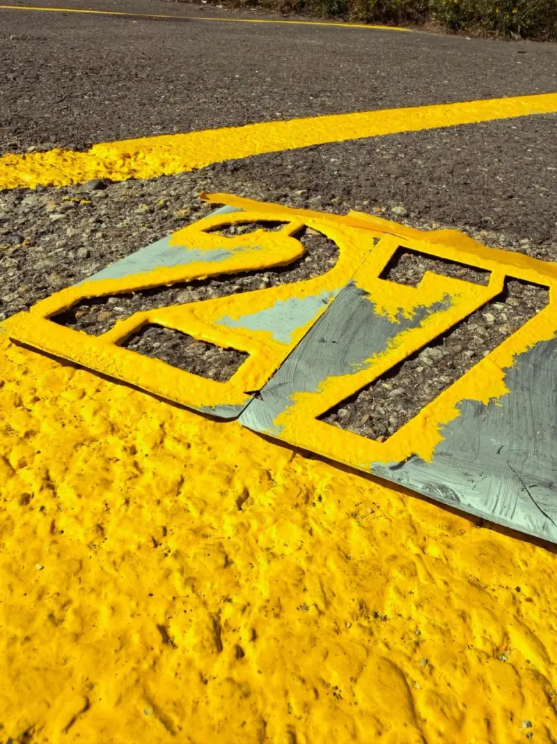 Numéro de place peint en jaune au pochoir sur l’enrobé